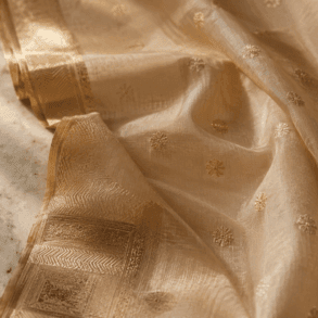 Pale gold Chanderi silk-cotton saree with zari border and floral butti motifs on white marble