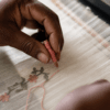 Weaver's hands placing discontinuous weft thread on a Jamdani loom