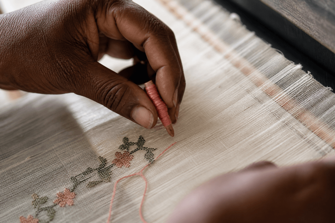 Weaver's hands placing discontinuous weft thread on a Jamdani loom