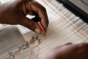 Weaver's hands placing discontinuous weft thread on a Jamdani loom