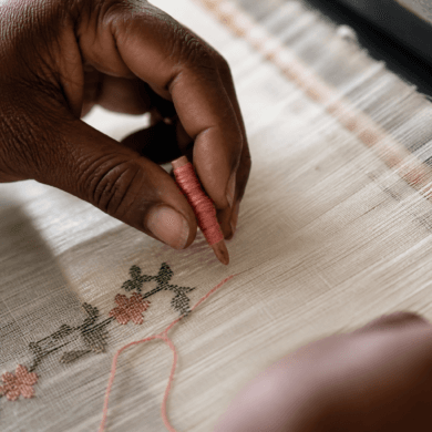 Weaver's hands placing discontinuous weft thread on a Jamdani loom