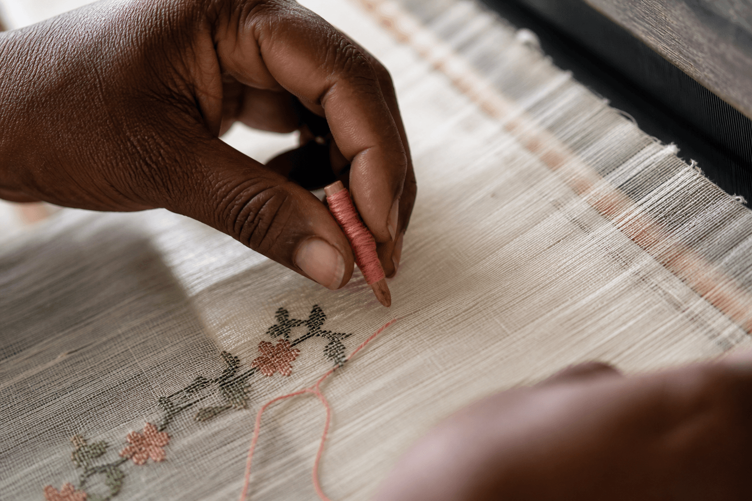 Weaver's hands placing discontinuous weft thread on a Jamdani loom