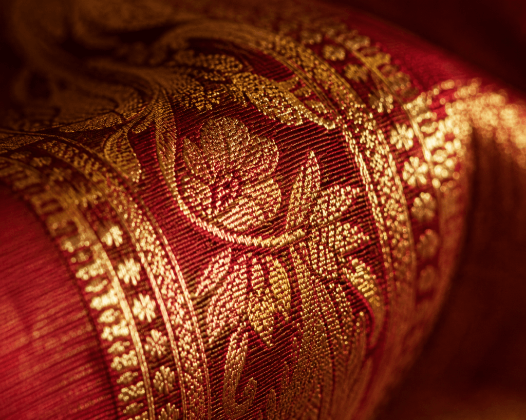 Close-up of gold zari thread on a silk saree border